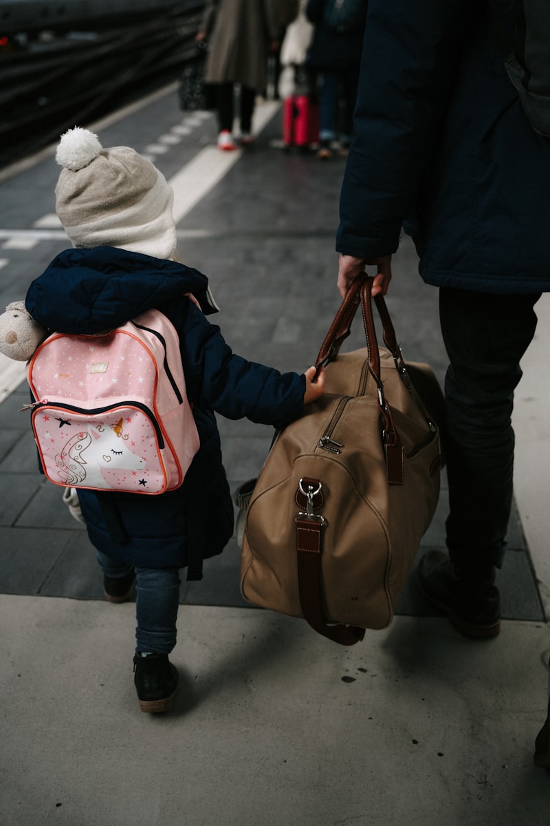 A child holds a bag, walking with a person.