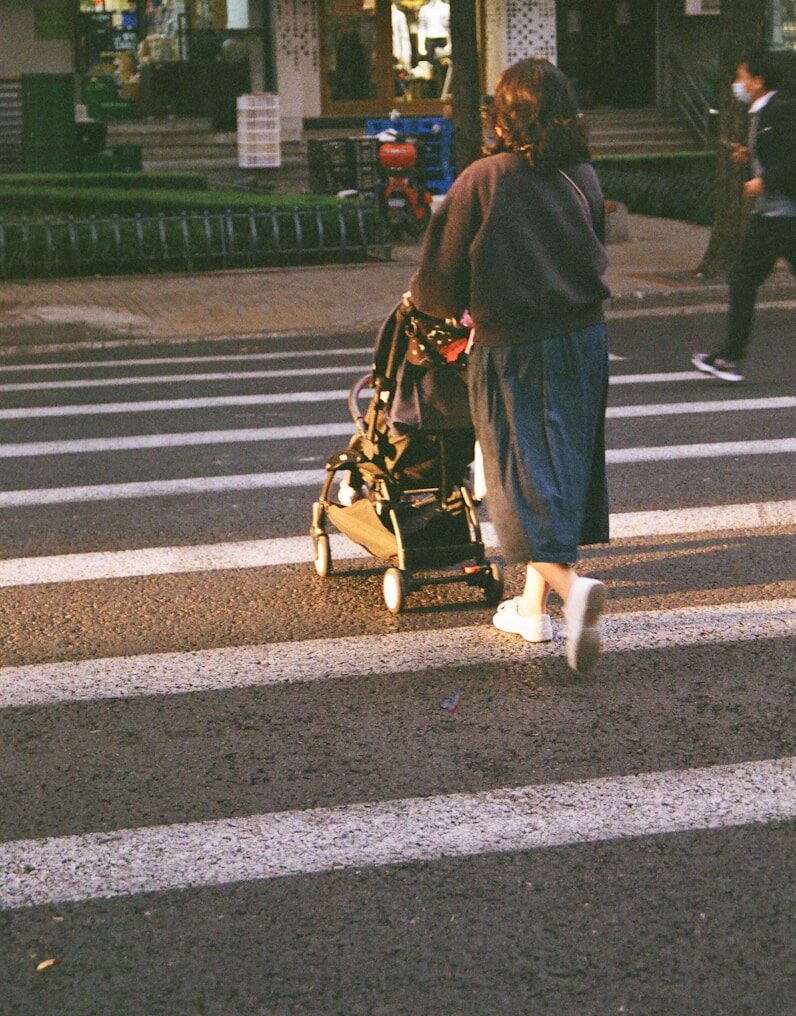 a person walking a stroller across a crosswalk