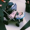 Parent pushing a baby in a stroller indoors